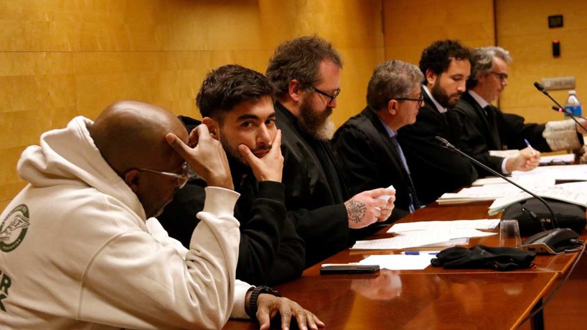 L'acusat, segon per l'esquerra, assegut entre el seu intèrpret i el seu advocat